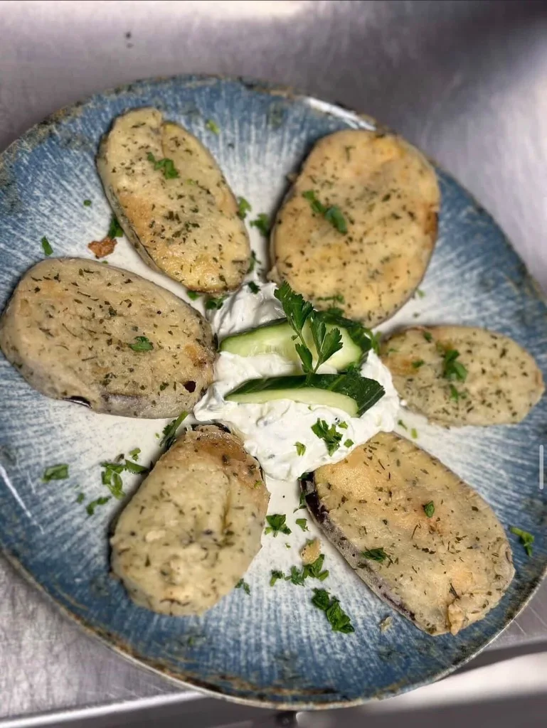 Überbackene Spezialität mit Kräutern auf Tzatziki