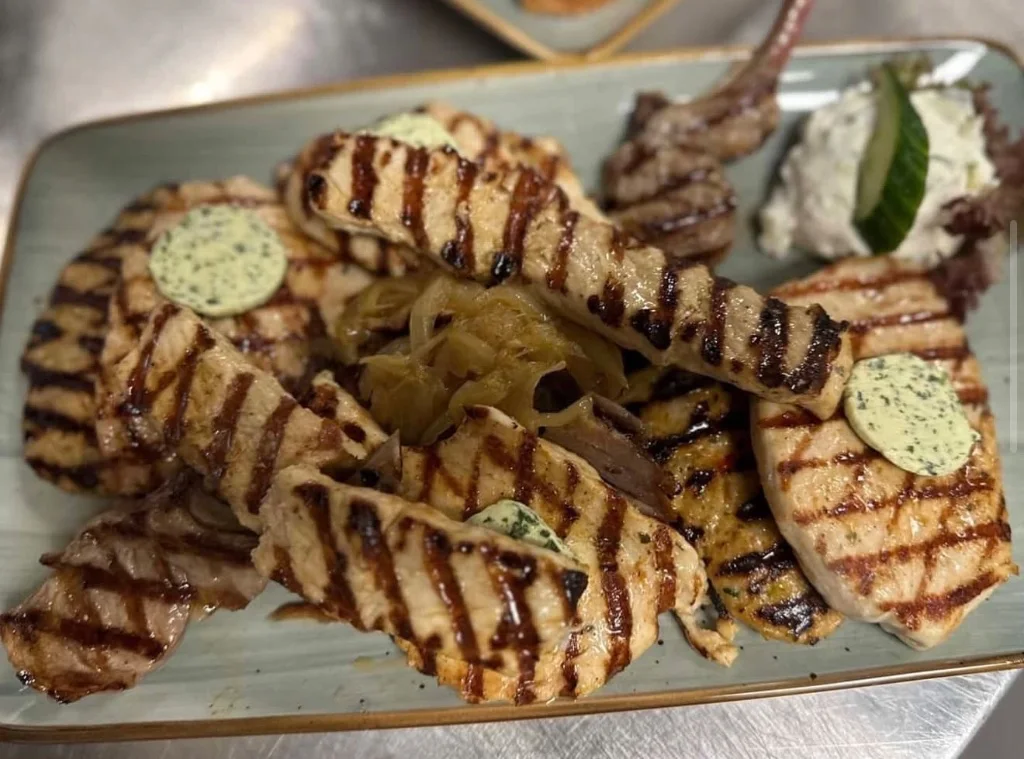 Grillplatte mit Lammkoteletts, Souvlaki und Kräuterbutter